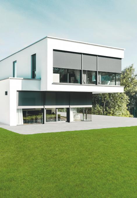 Maison témoin moderne, au crépuscule, éclairée de l'intérieur, brise-soleil