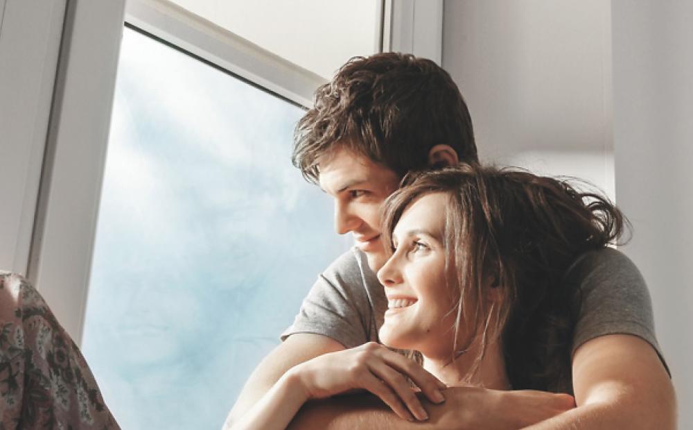 Un couple est blotti près d'une fenêtre avec vue sur l'extérieur