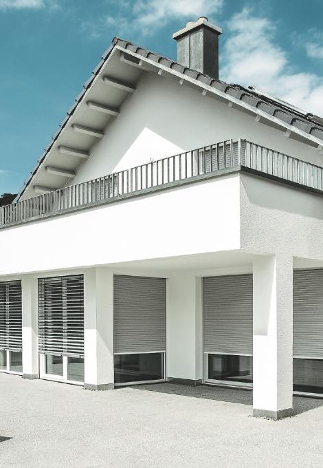 Maison individuelle, toit pointu, balcon, le jour, volets roulants descendus au 3/4