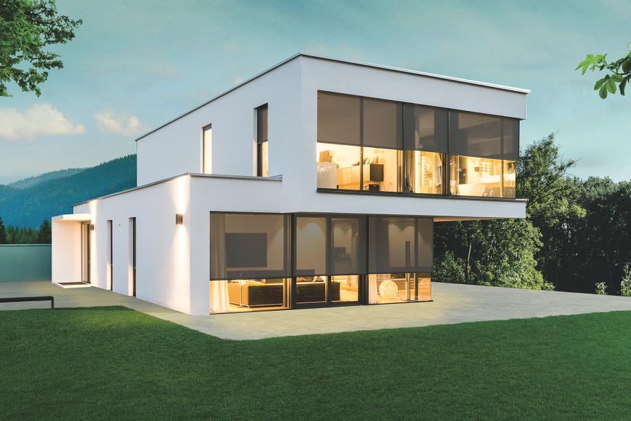 Maison témoin moderne, au crépuscule, éclairée de l'intérieur, stores toiles