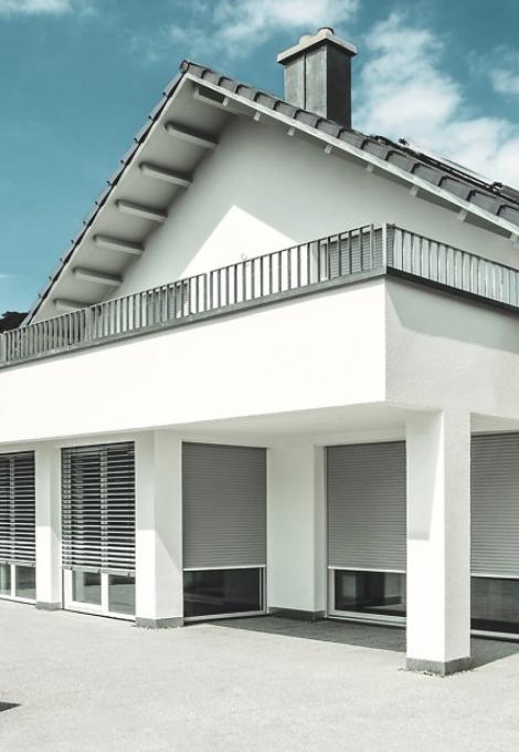 Maison individuelle, toit pointu, balcon, le jour, volets roulants descendus au 3/4