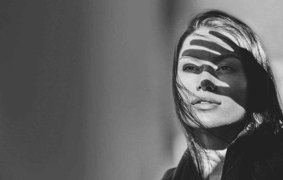 Femme se protégeant avec la main de la lumière éblouissante, noir/blanc