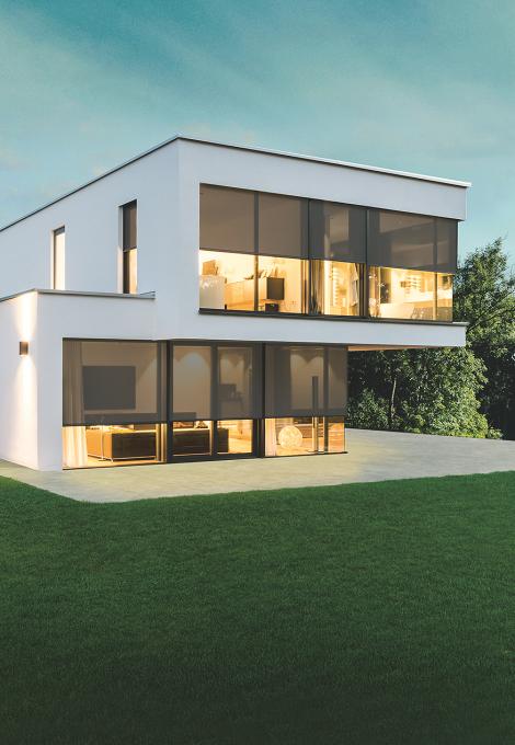 Maison témoin moderne, au crépuscule, éclairée de l'intérieur, stores toiles