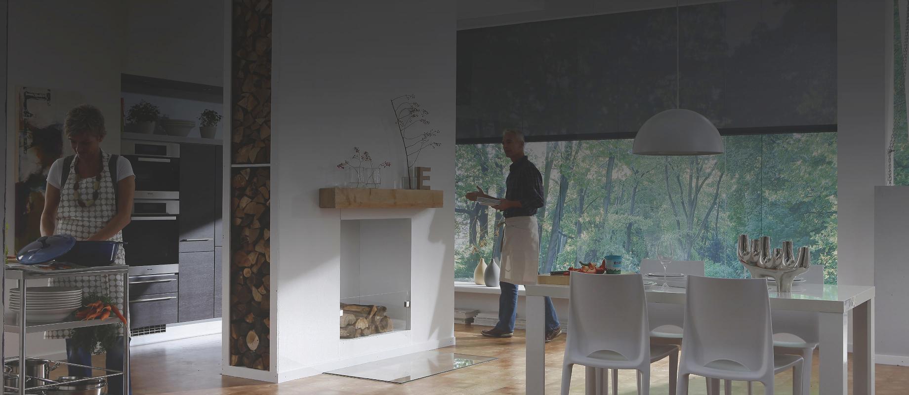 Femme cuisinant dans une cuisine ouverte donnant sur la salle à manger + un homme