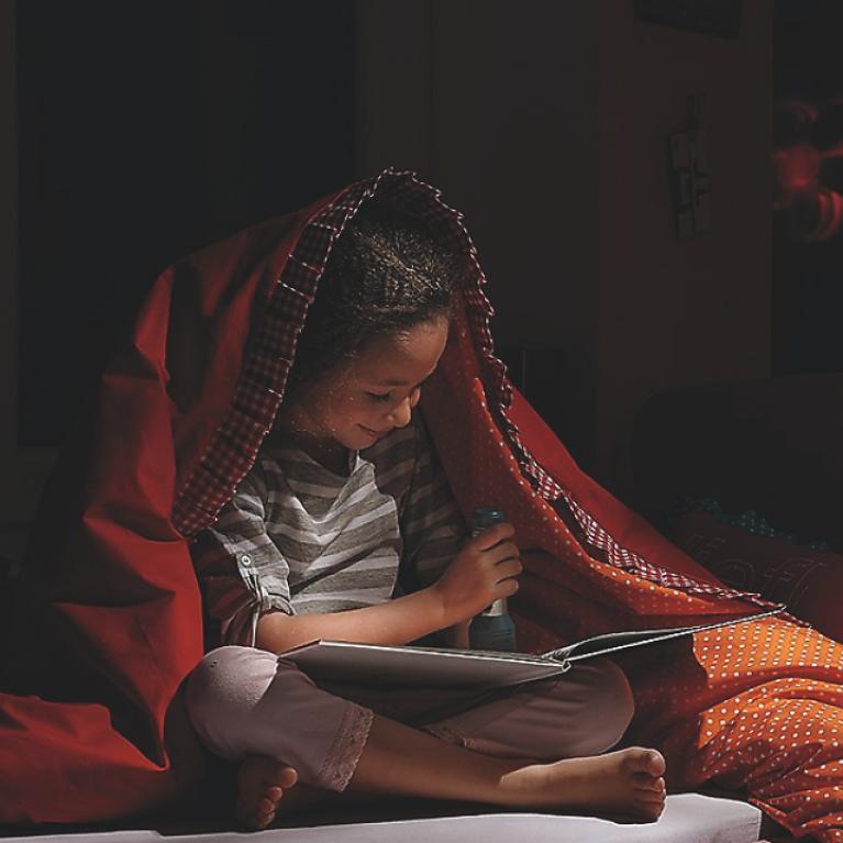 Enfant lisant un livre Enfant en train de lire avec couverture sur la tête dans l'obscurité