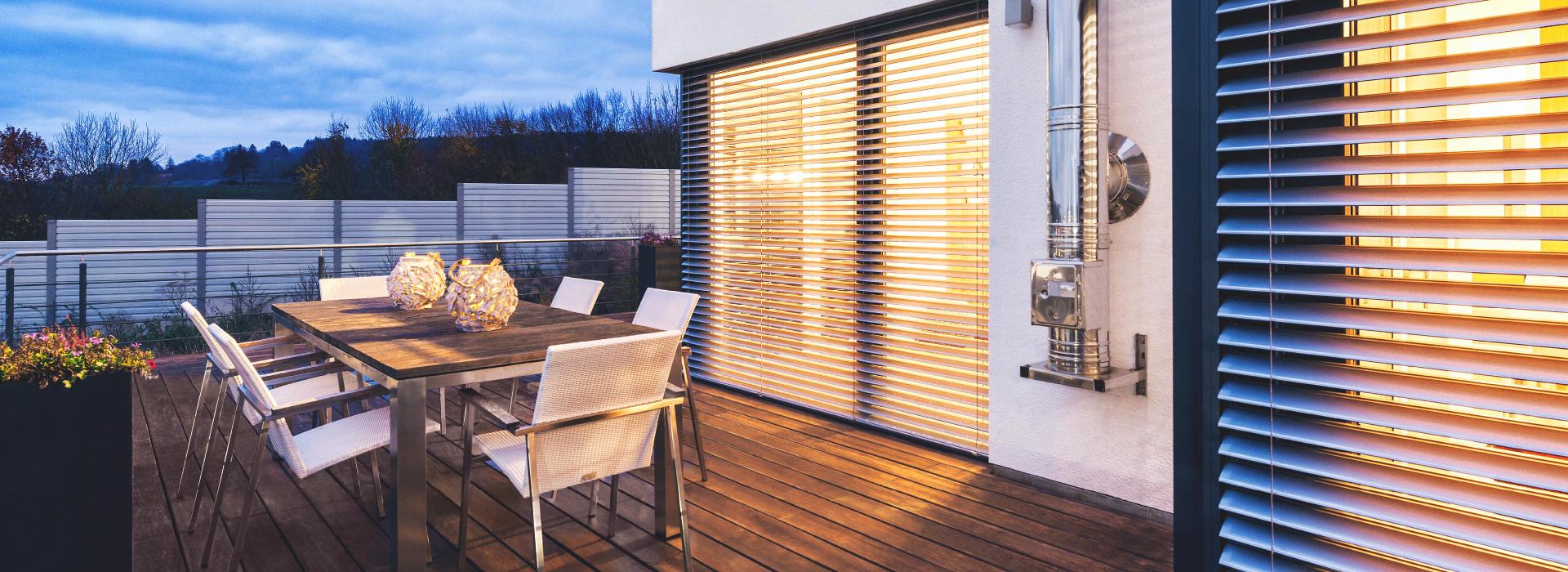 Terrasse avec mobilier d'extérieur, au crépuscule, avec vue sur brise-soleil ROMA à moitié inclinés