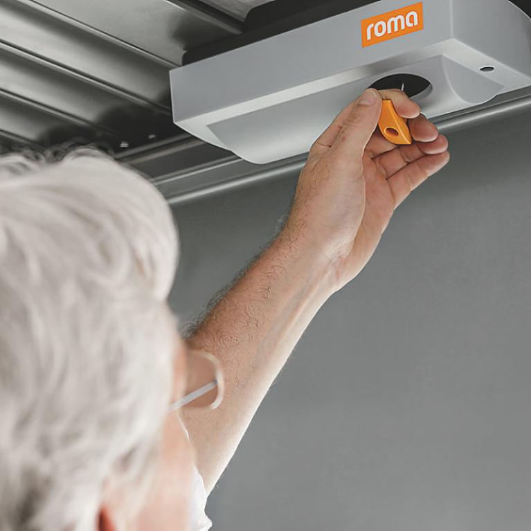 Portes de garage ROMA - Déverrouillage d'urgence Un homme montre le déverrouillage de secours ROMA installé sur sa porte de garage