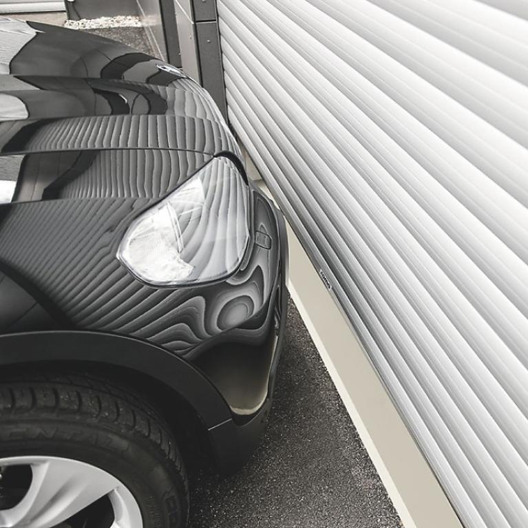 Portes de garage ROMA Vue latérale partie d'une voiture BMW série 1 devant porte de garage