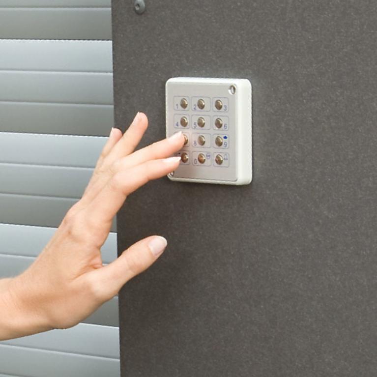 ROMA - Digicode Gros plan mur à côté de la porte de garage avec une main qui est en train de composer un numéro sur le digicode