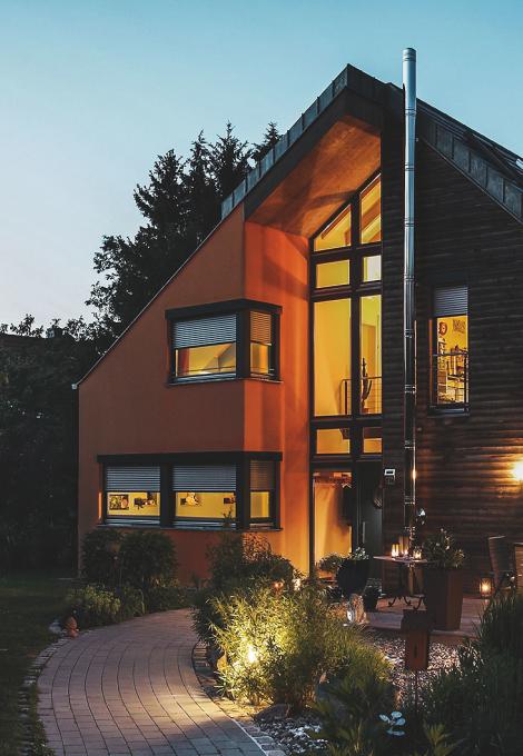 Maison, au crépuscule, éclairée de l'intérieur, volets roulants à moitié descendus