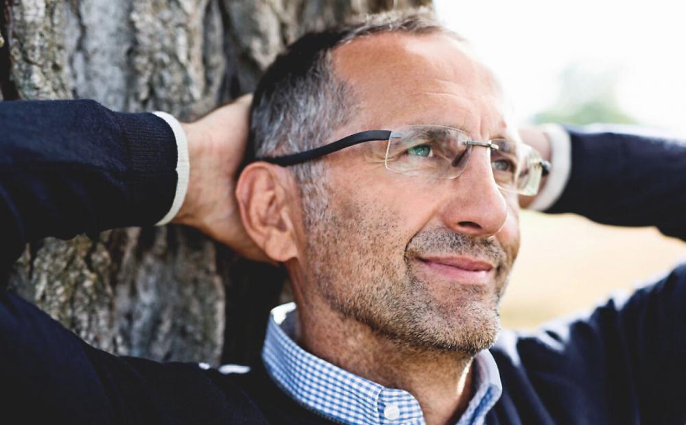 Vue détaillée homme adossé à un arbre avec les bras pliés derrière la tête