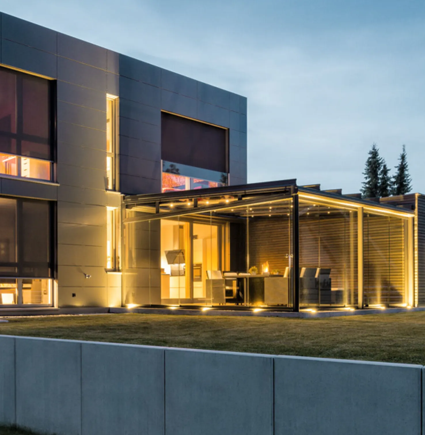 Maison moderne au crépuscule avec éclairage intérieur et Stores toiles rénovation abaissés